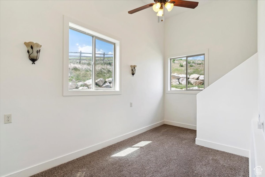 Carpeted spare room featuring ceiling fan and baseboards