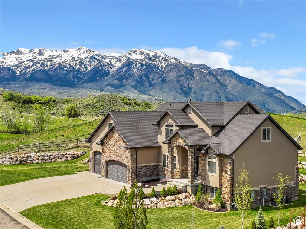 View of front facade featuring stone siding, a garage, a mountain view, and driveway