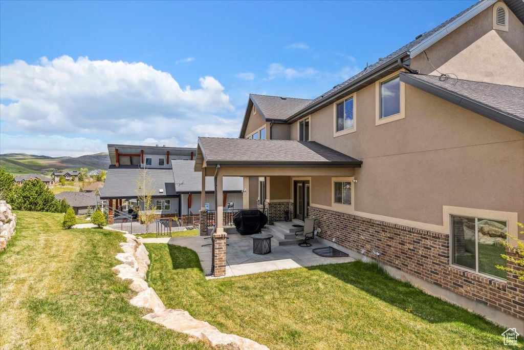 Back of property featuring a patio area, a lawn, and stucco siding
