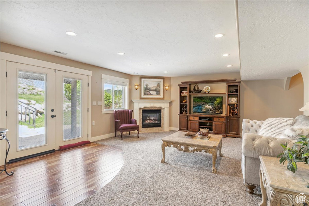 Living area featuring recessed lighting, a premium fireplace, wood finished floors, french doors, and baseboards