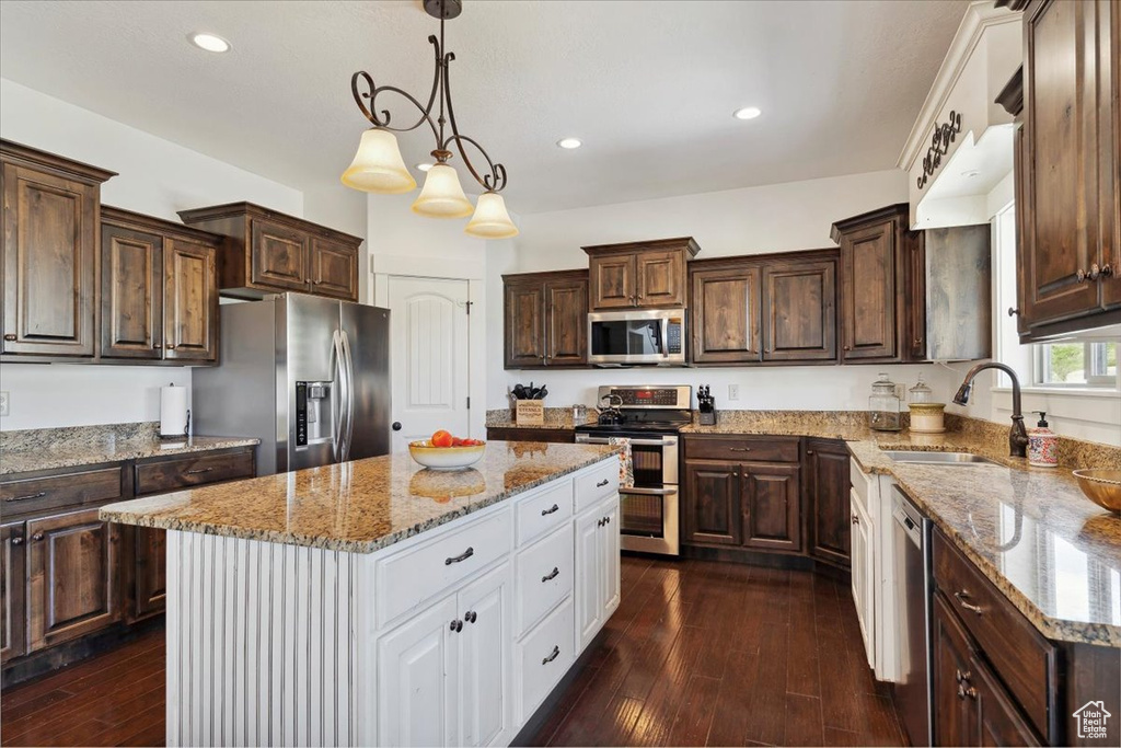 Kitchen featuring stainless steel appliances, a sink, white cabinets, dark brown cabinets, and recessed lighting
