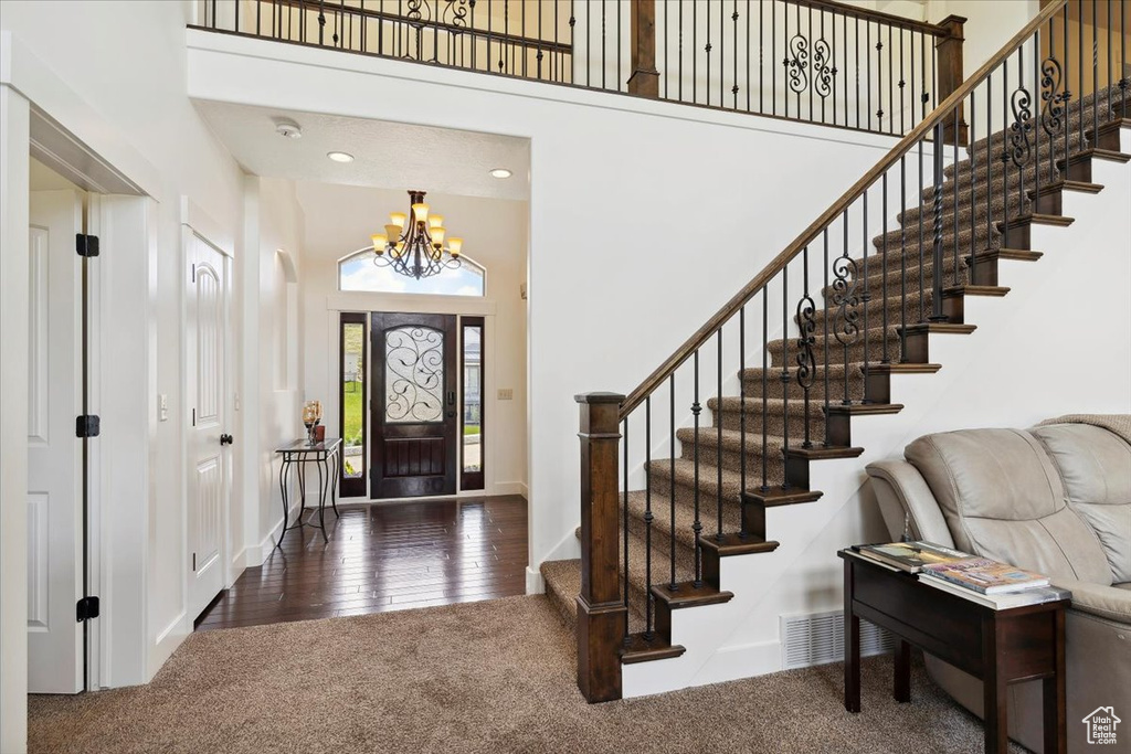 Foyer with a high ceiling, carpet flooring, a chandelier, stairs, and baseboards