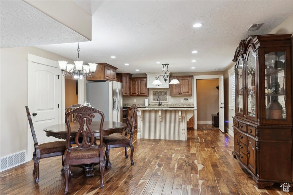 Dining space with dark wood finished floors, a chandelier, recessed lighting, baseboards, and a textured ceiling