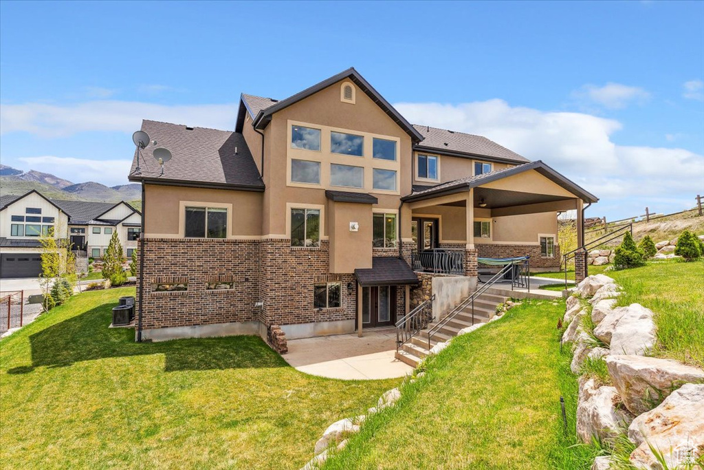 Rear view of house with stucco siding, a patio area, stairway, and a mountain view