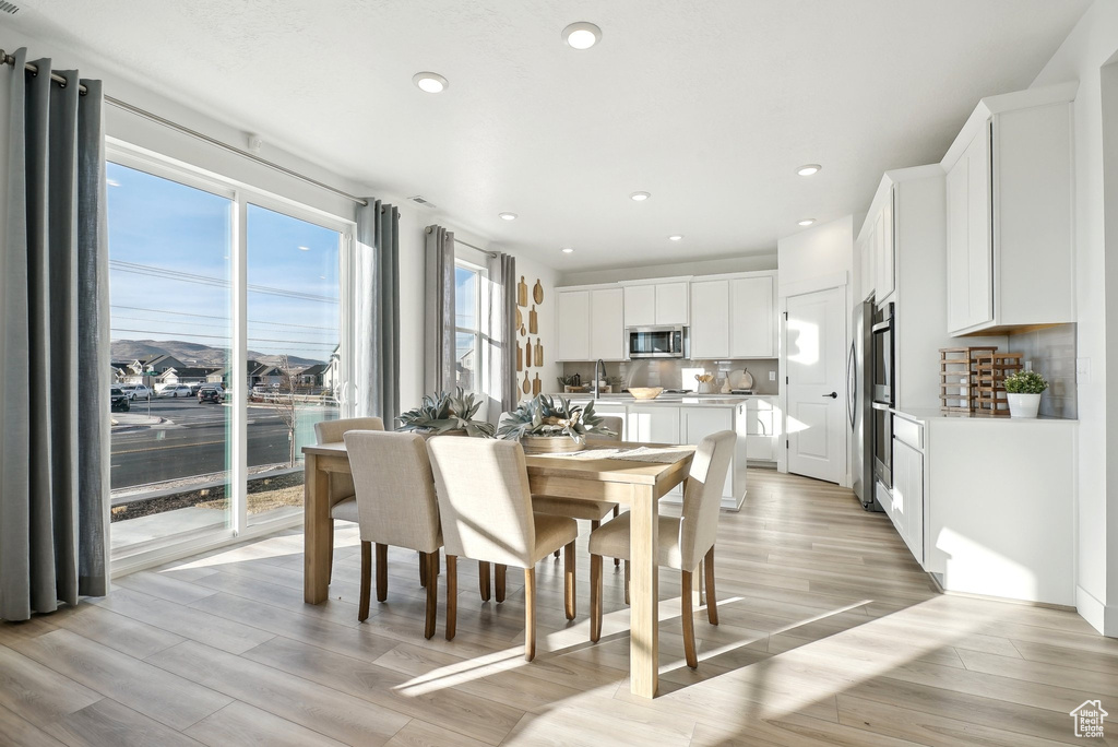 Dining room with light wood-style floors and recessed lighting