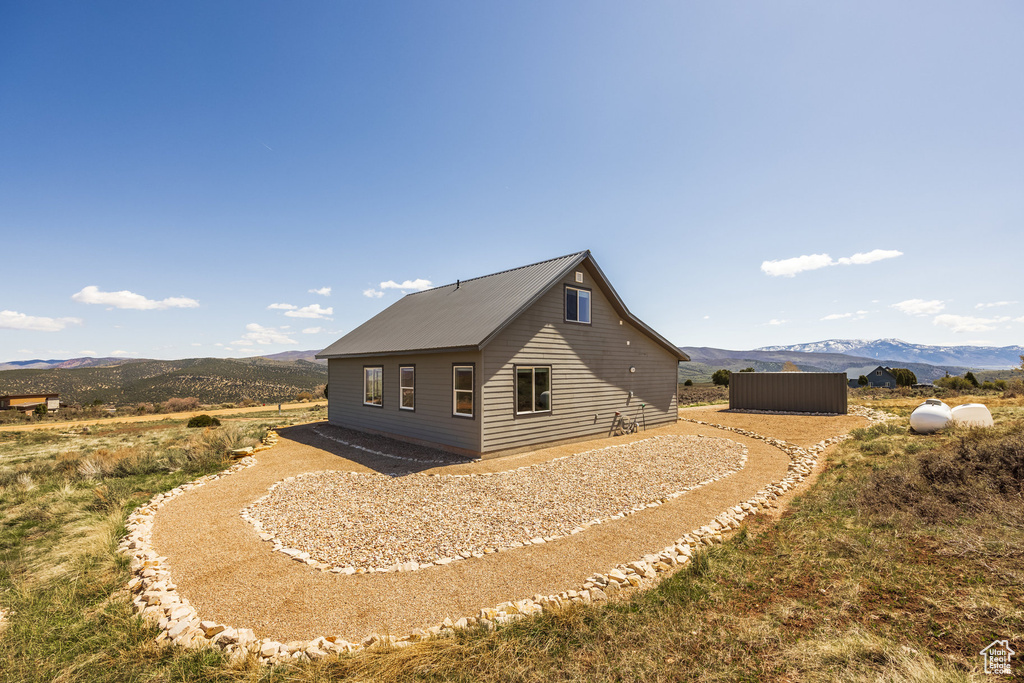 View of property exterior featuring a mountain view, an outbuilding, and a storage shed