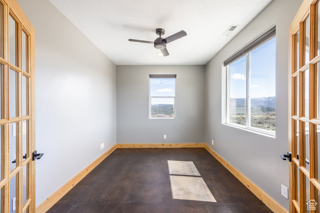 Unfurnished room with french doors, healthy amount of natural light, a ceiling fan, and baseboards