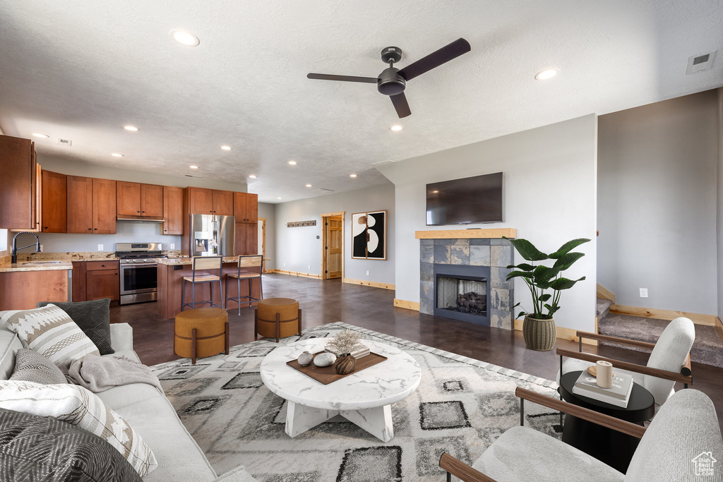Living room featuring baseboards, a ceiling fan, recessed lighting, and a tiled fireplace