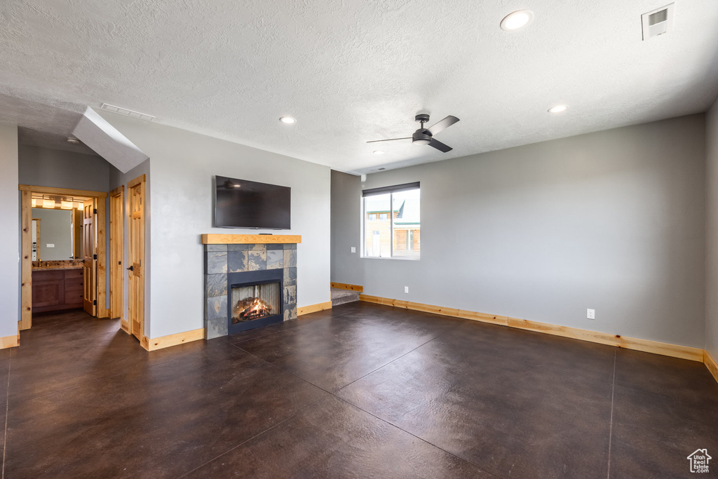 Unfurnished living room featuring baseboards, a tiled fireplace, ceiling fan, recessed lighting, and a textured ceiling