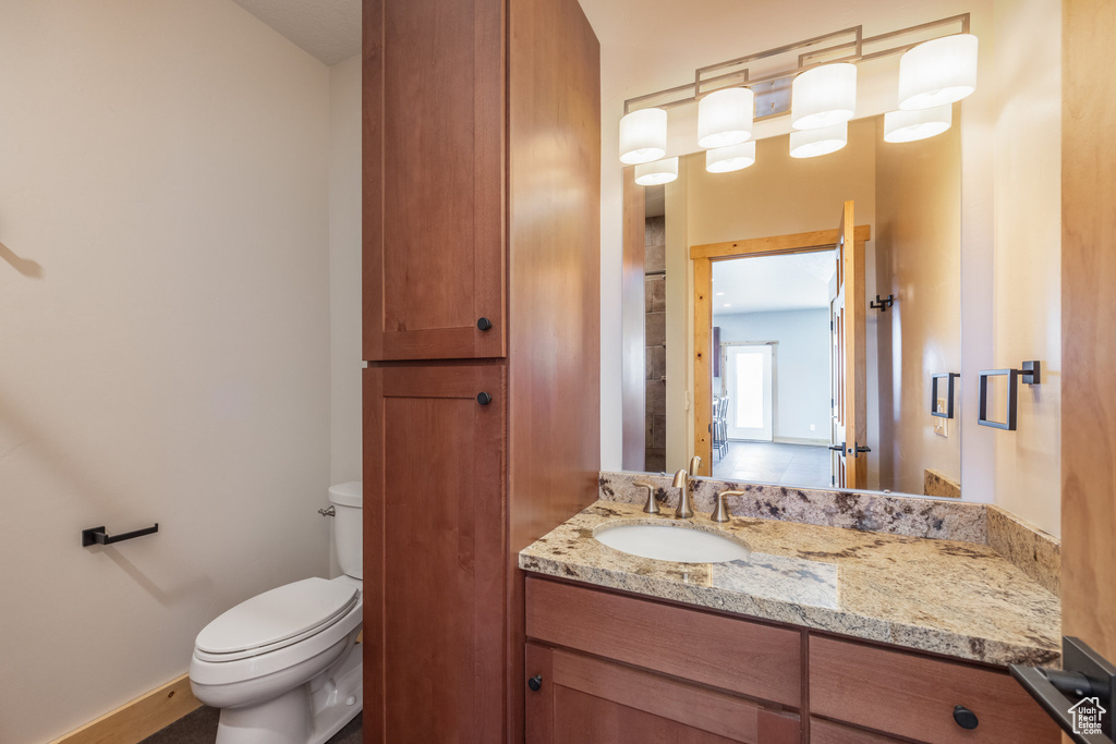 Half bath featuring toilet, vanity, and baseboards