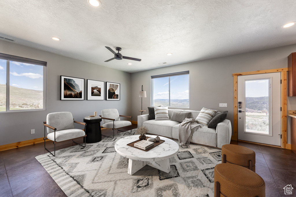 Living room featuring plenty of natural light, recessed lighting, ceiling fan, baseboards, and a textured ceiling