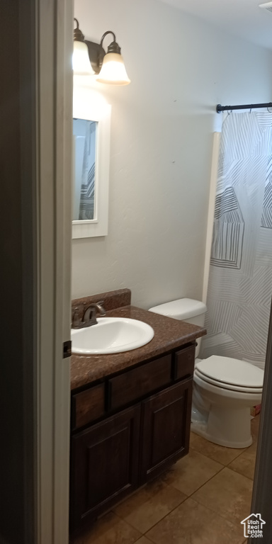 Full bath with tile patterned flooring, vanity, toilet, and curtained shower