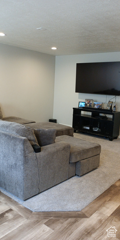 Living area with recessed lighting, a textured ceiling, and wood finished floors
