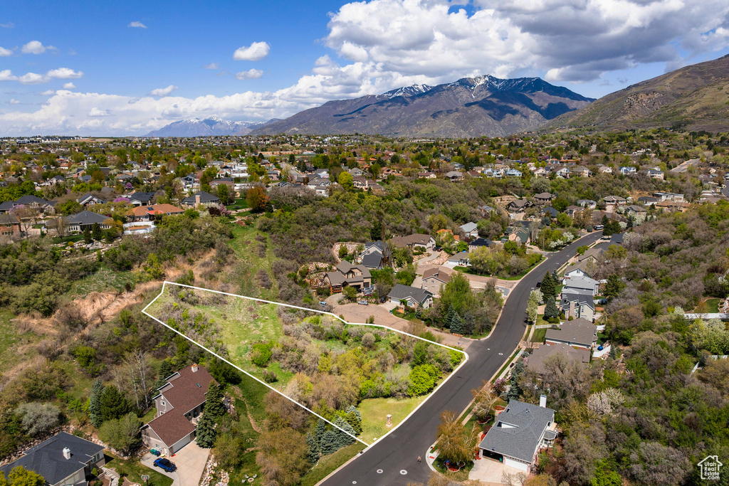 Aerial view of residential area with property boundaries highlighted and a mountain backdrop