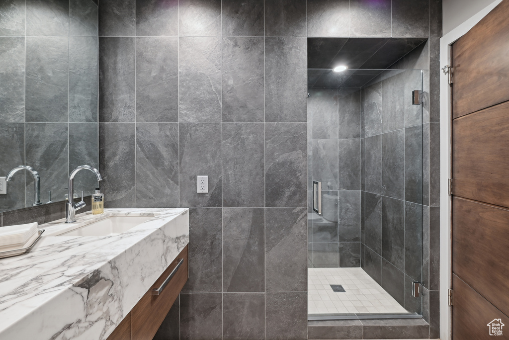 Full bath with a shower stall, vanity, and tile walls