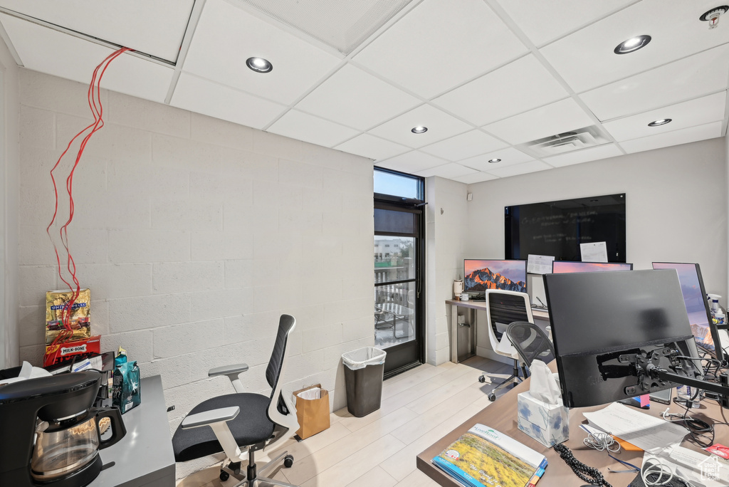 Office area with recessed lighting, concrete block wall, wood finished floors, and a drop ceiling