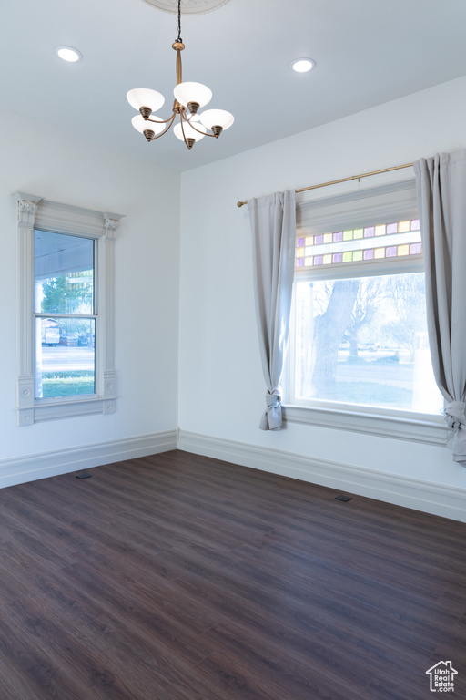 Unfurnished room featuring a chandelier, dark wood finished floors, baseboards, and recessed lighting