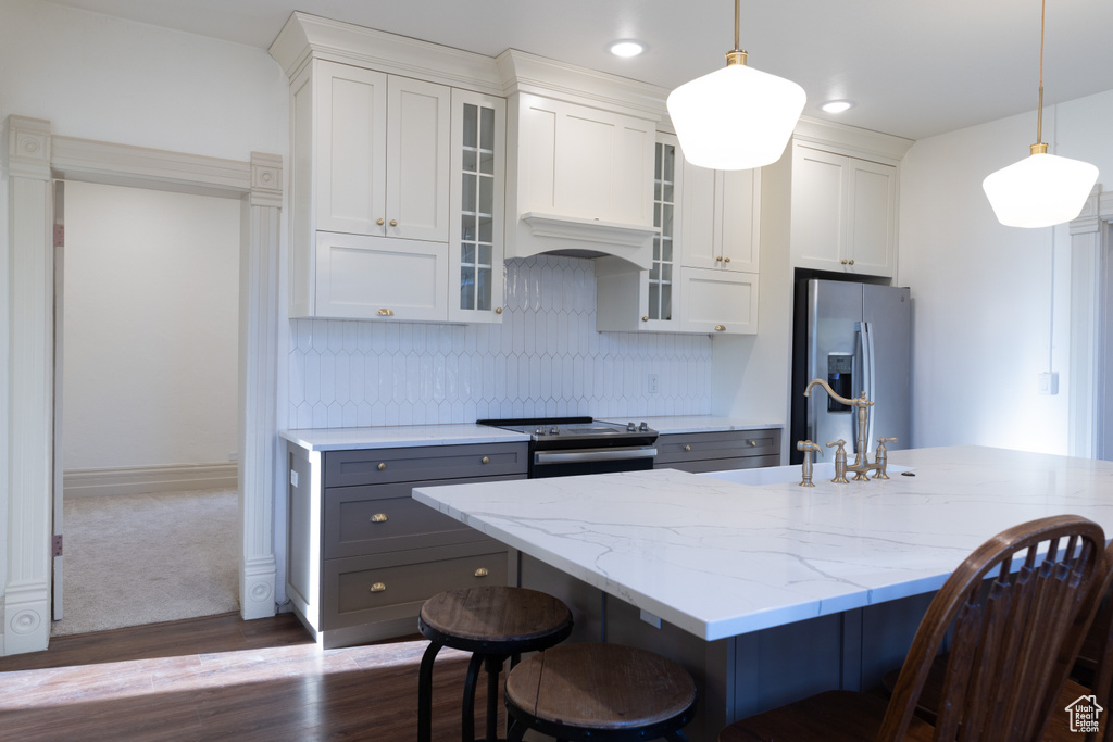 Kitchen with appliances with stainless steel finishes, a breakfast bar area, dark wood-type flooring, a sink, and recessed lighting