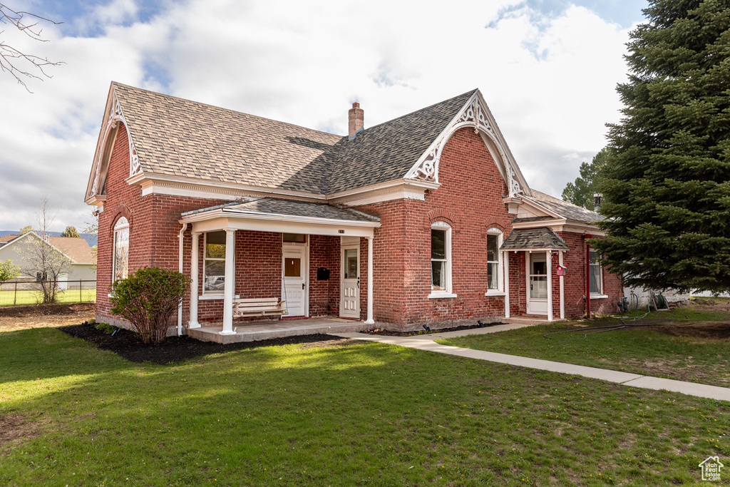 View of front of property with brick siding, roof with shingles, and a chimney