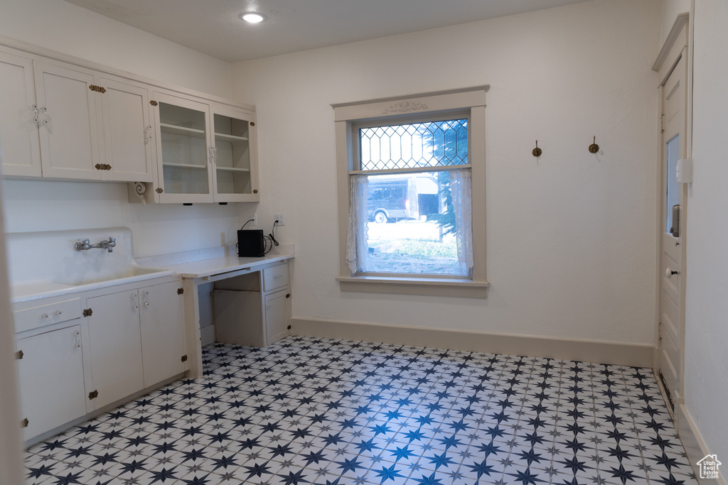 Kitchen with light countertops, white cabinets, light floors, a sink, and glass insert cabinets