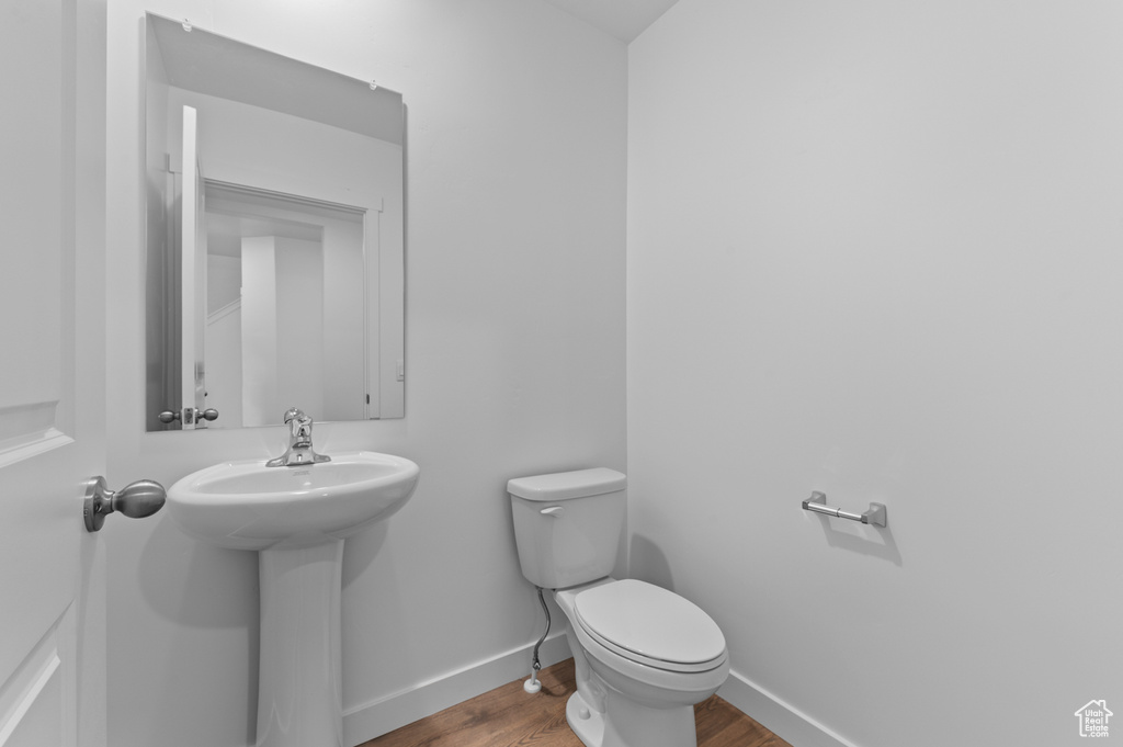 Half bathroom with wood finished floors, toilet, baseboards, and a sink