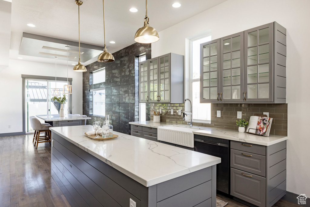 Kitchen with gray cabinets, a center island, a sink, dishwashing machine, and recessed lighting
