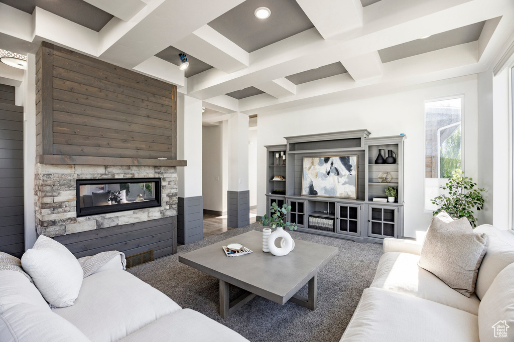 Carpeted living area featuring a stone fireplace, beam ceiling, coffered ceiling, and recessed lighting