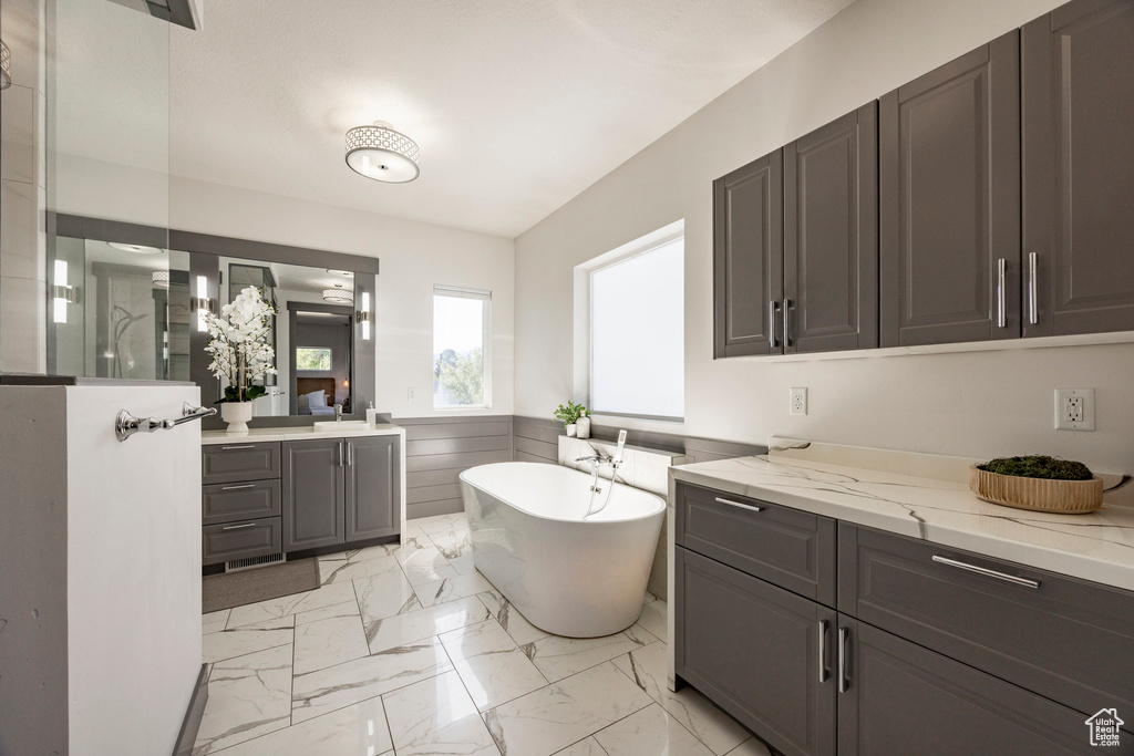 Full bathroom featuring wainscoting, marble finish floors, a soaking tub, a walk in shower, and vanity