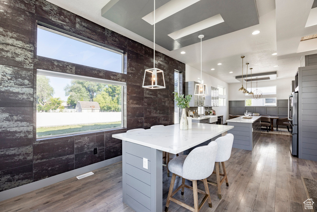 Kitchen with a kitchen island, plenty of natural light, dark wood-style flooring, freestanding refrigerator, and tile walls