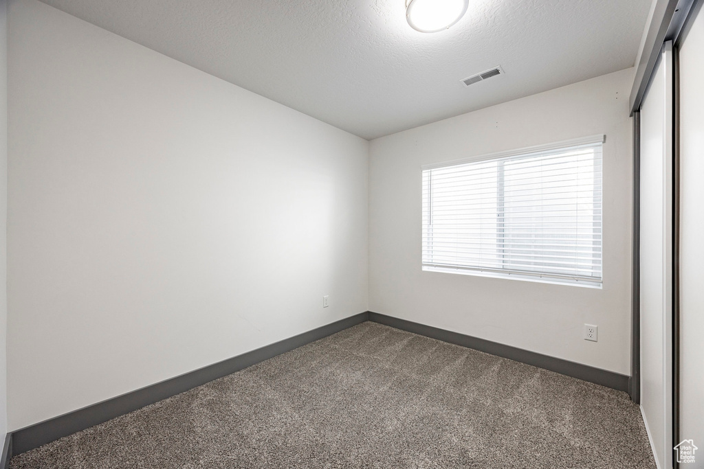 Spare room with dark colored carpet and baseboards