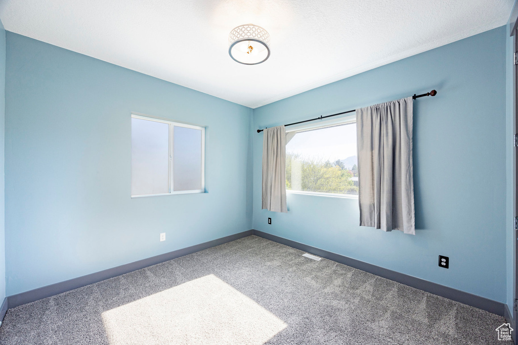 Carpeted spare room featuring baseboards