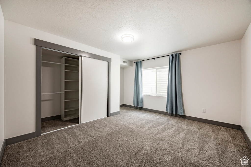 Unfurnished bedroom featuring carpet flooring, a closet, baseboards, and a textured ceiling