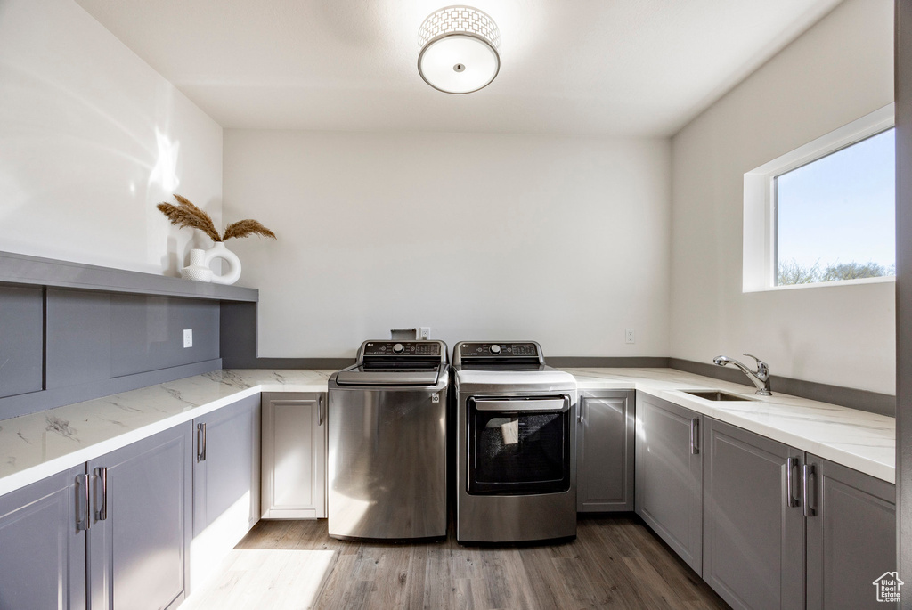 Washroom featuring cabinet space, washing machine and dryer, and wood finished floors