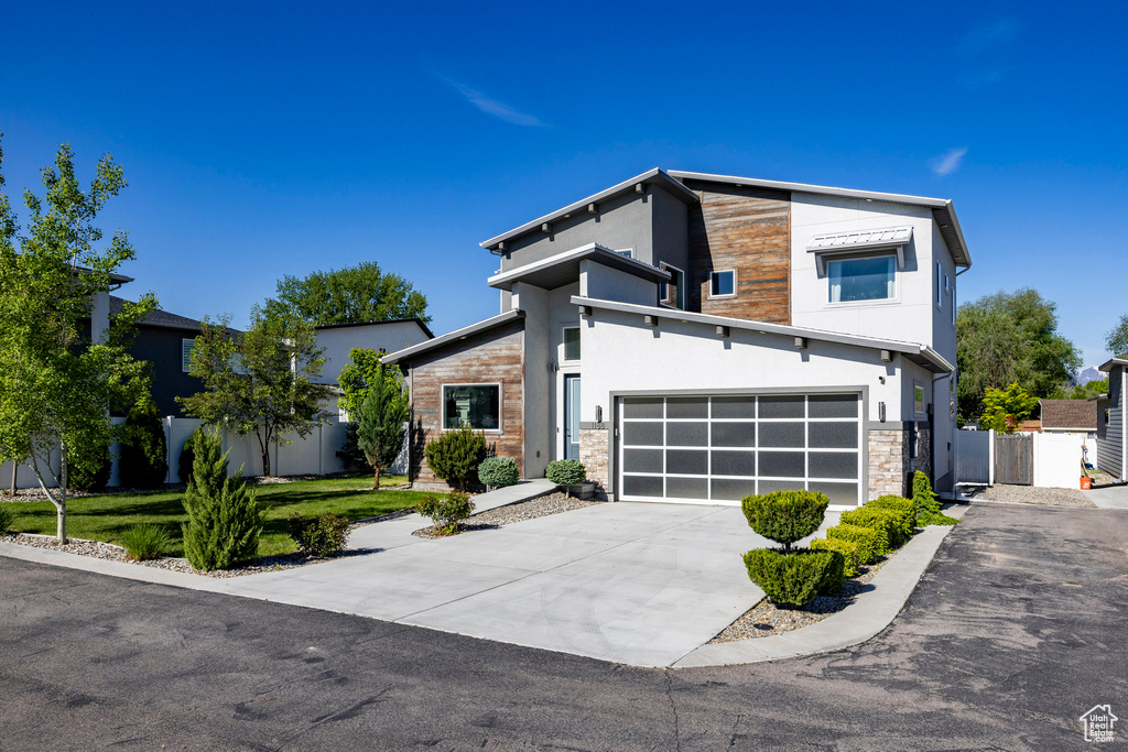 Contemporary home with concrete driveway, stone siding, stucco siding, and a garage