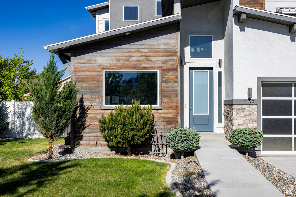 Doorway to property with stucco siding and a lawn