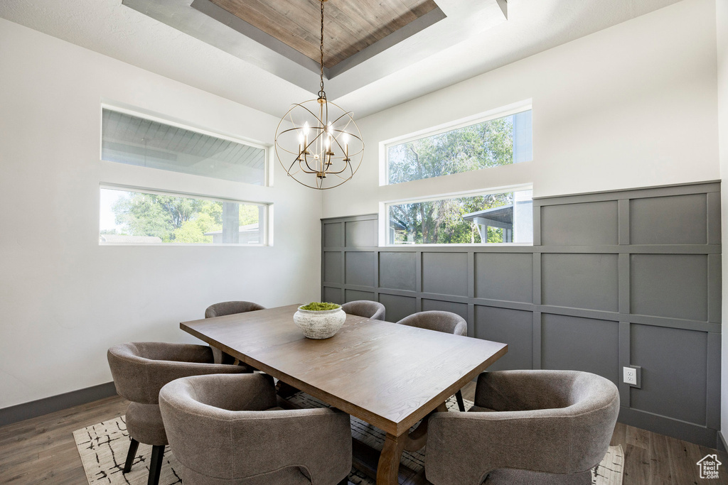 Dining area featuring a decorative wall, a raised ceiling, a chandelier, dark wood-type flooring, and a high ceiling