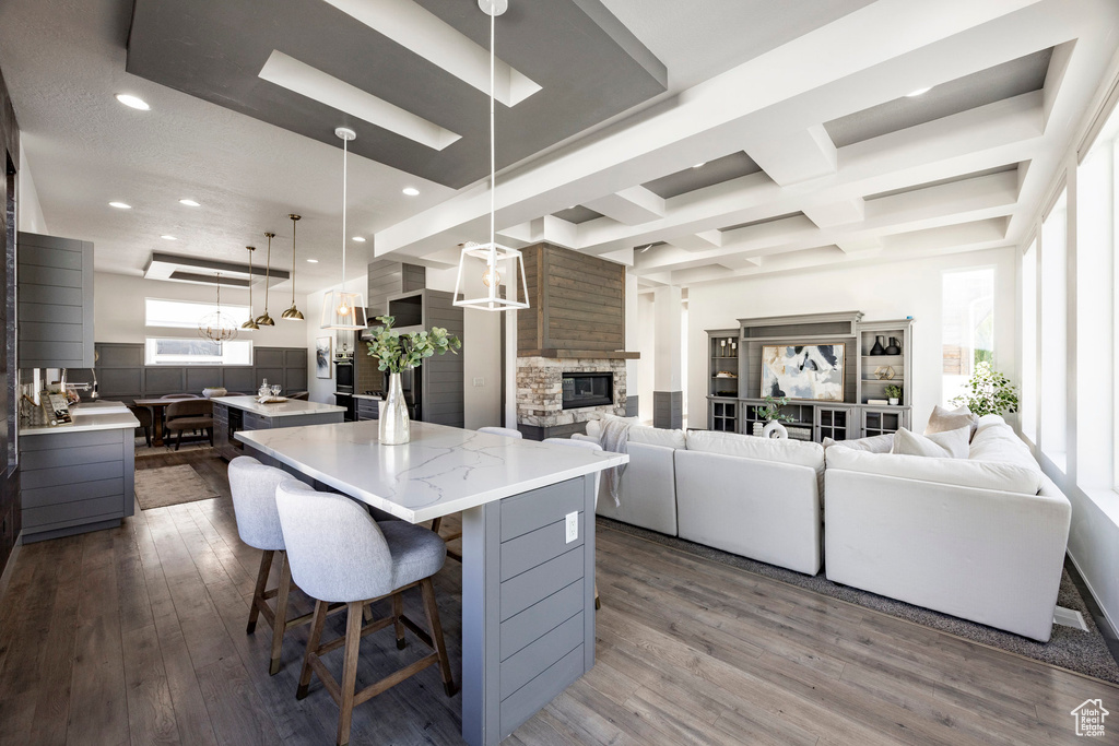 Kitchen featuring a spacious island, a chandelier, dark wood-type flooring, a kitchen breakfast bar, and a fireplace