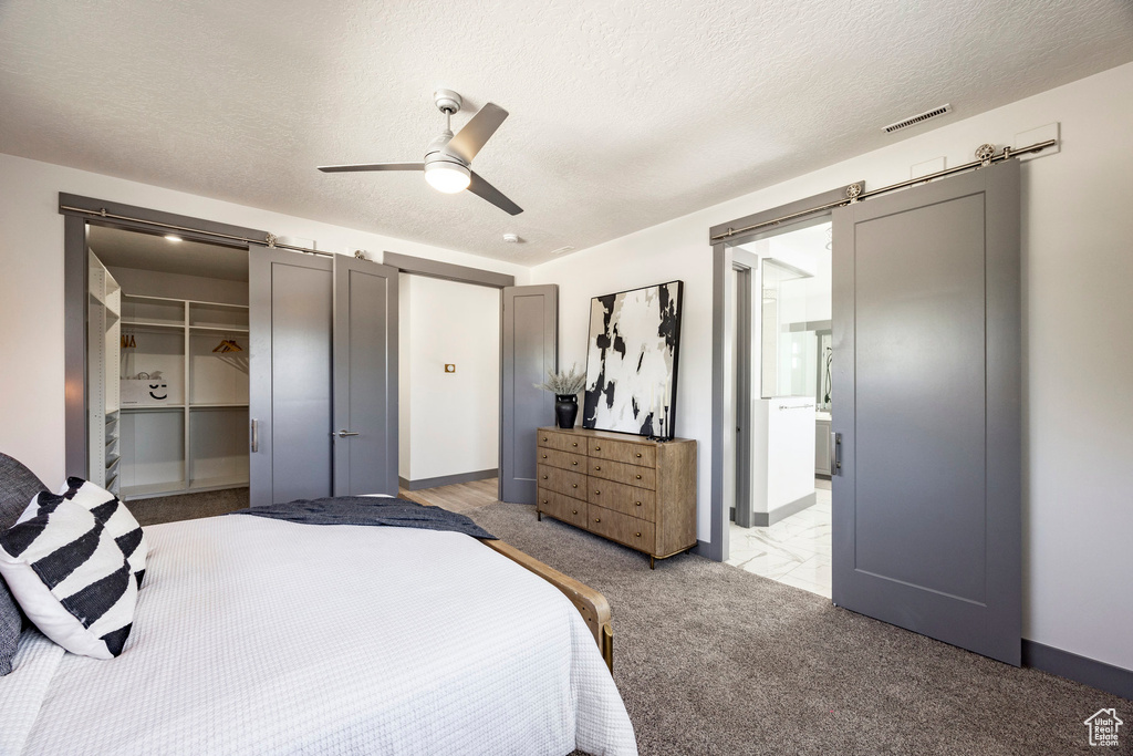 Carpeted bedroom featuring a textured ceiling, ceiling fan, a spacious closet, and a closet
