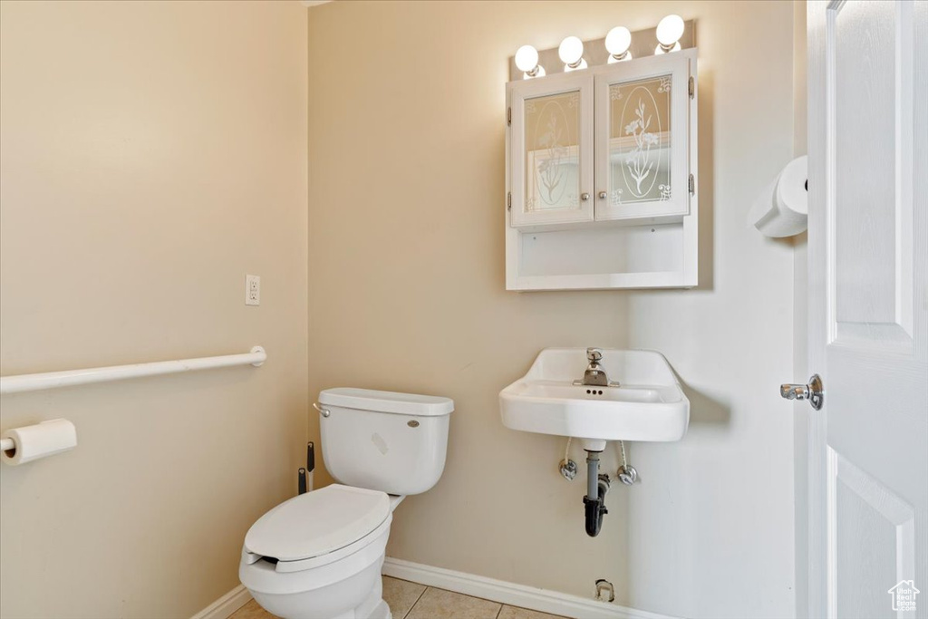 Bathroom with toilet, baseboards, and tile patterned flooring