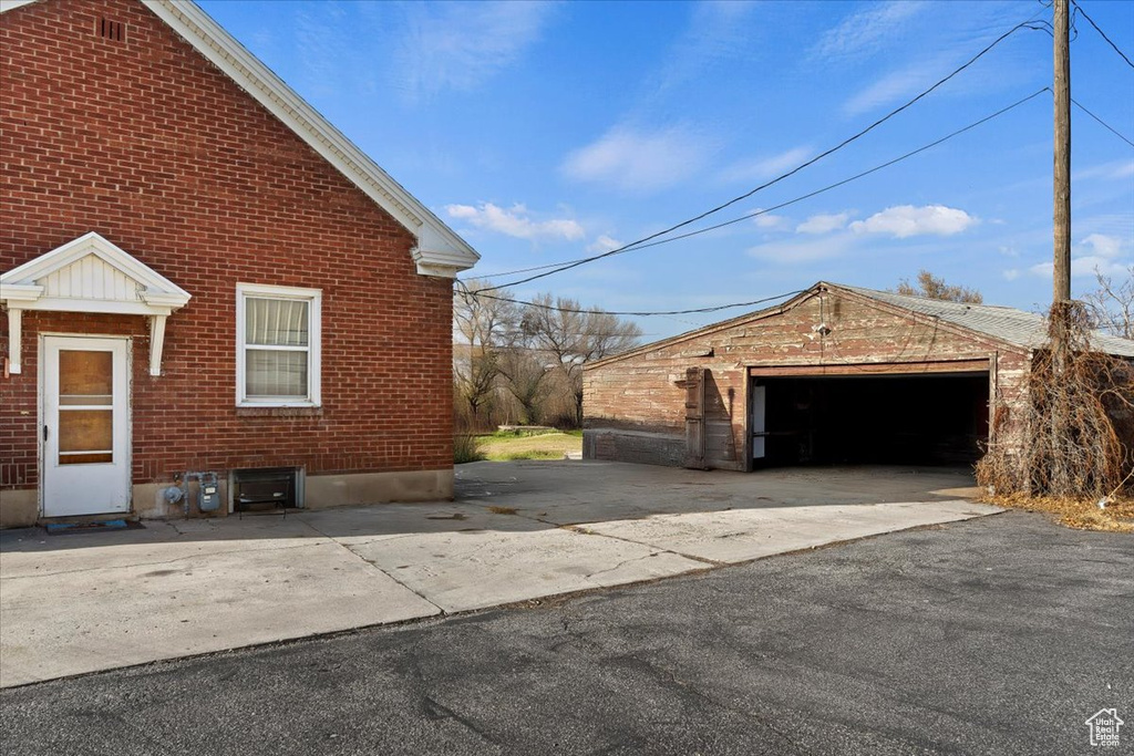 View of property exterior with brick siding, an outbuilding, and a garage
