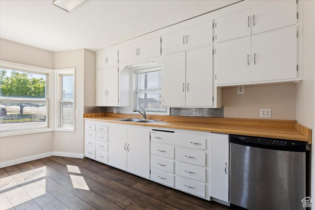 Kitchen featuring dishwasher, a sink, dark wood-type flooring, baseboards, and white cabinetry