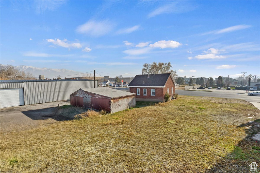 Back of house with an outdoor structure and a yard