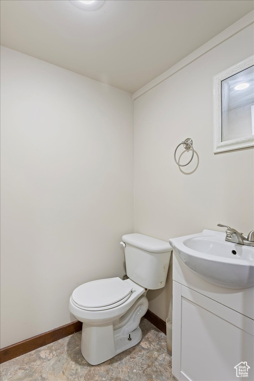 Bathroom featuring baseboards, toilet, vanity, and stone finish flooring