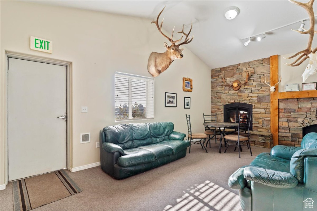 Carpeted living room with a fireplace and high vaulted ceiling