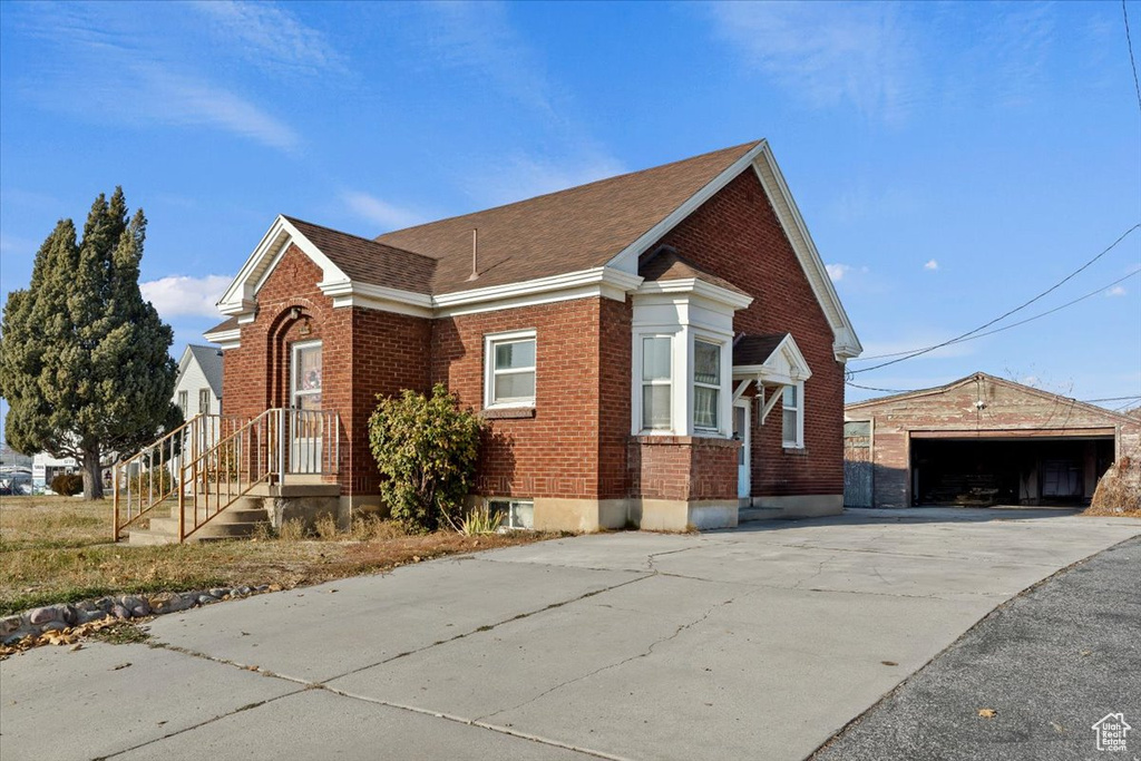 View of front of property with brick siding, an outdoor structure, and a garage