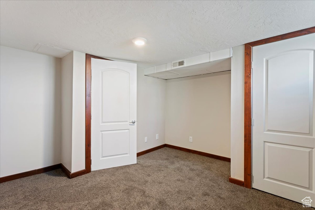 Finished basement with carpet flooring, a textured ceiling, and baseboards