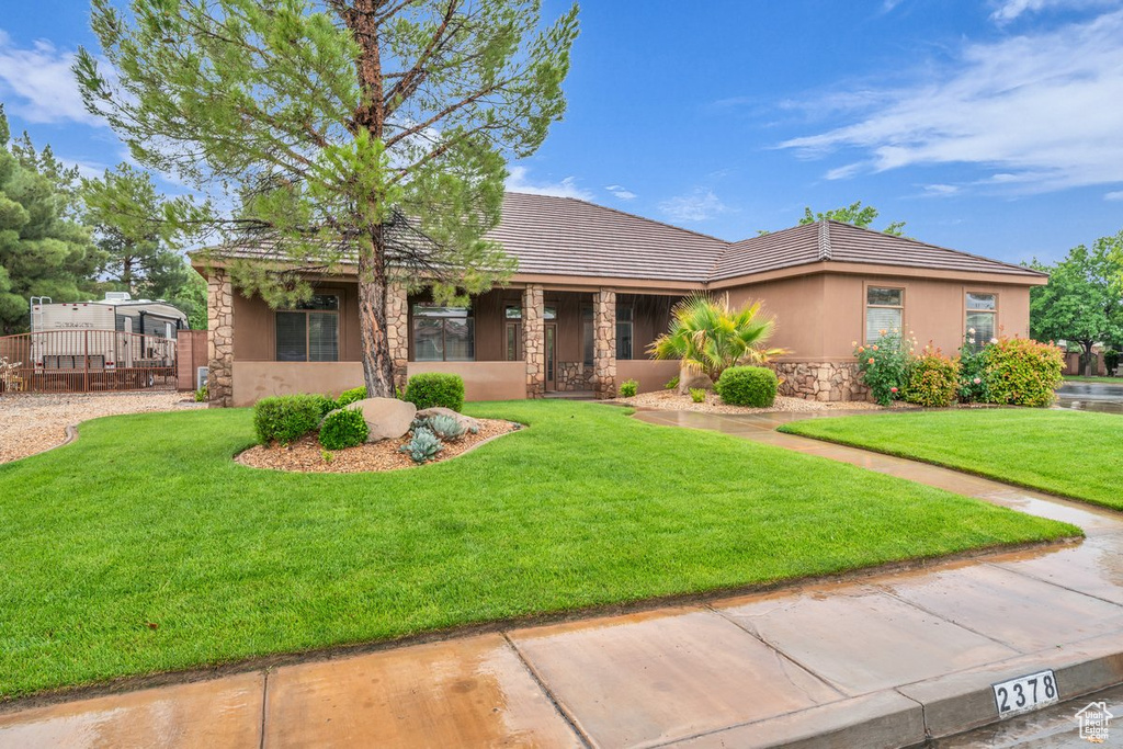 View of front of home featuring stone siding, a front lawn, a tile roof, and stucco siding