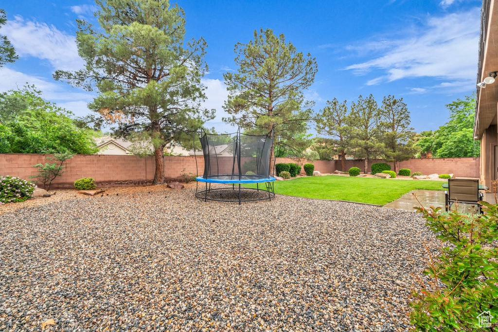 View of yard featuring a trampoline and a patio