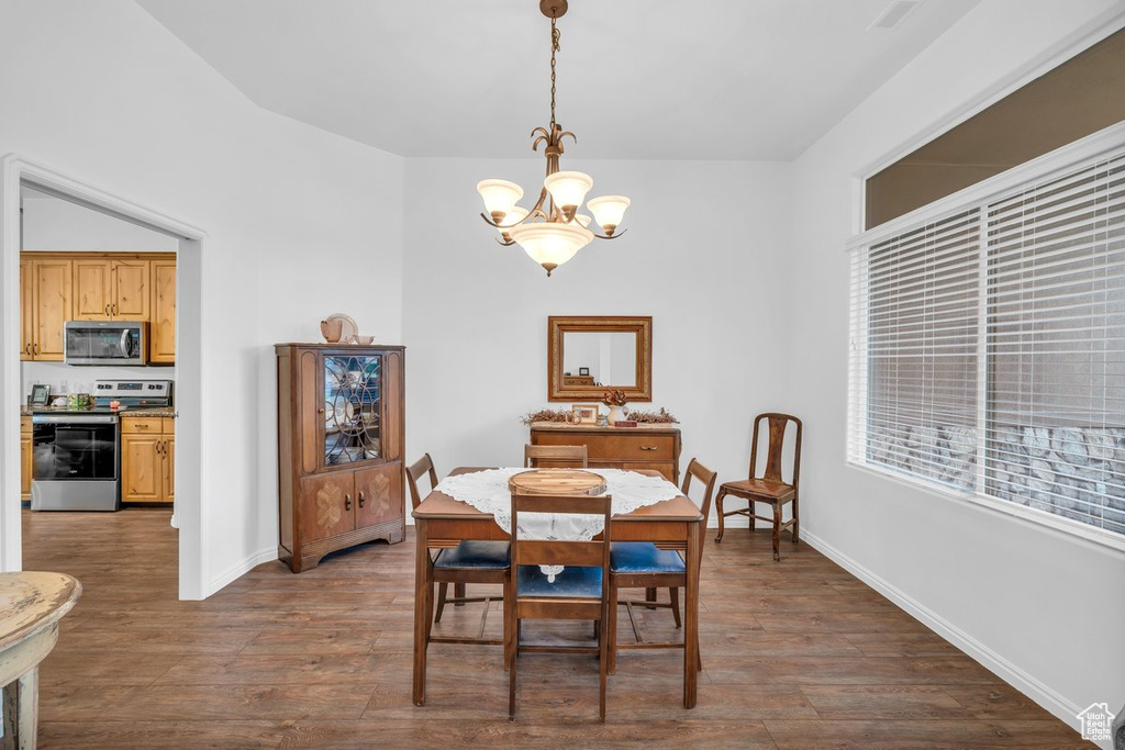 Dining room featuring a chandelier, dark wood-style flooring, and baseboards