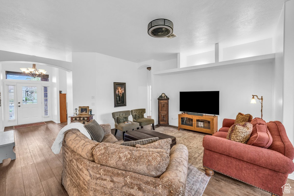Living room with a chandelier, arched walkways, and wood finished floors